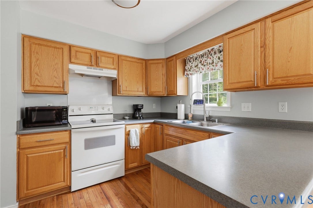 Kitchen featuring wood-finish cabinetry, a window over the sink, and L-shaped countertops