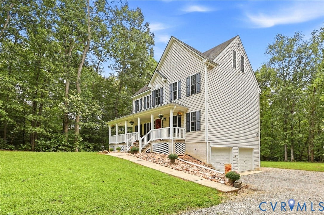 Traditional-style home featuring siding exterior, an expansive covered porch, and a two-car garage