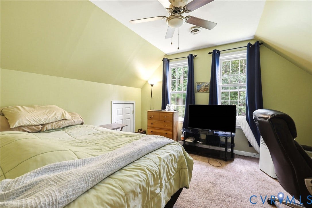 Bedroom featuring a ceiling fan, dual windows with natural light, and sloped ceilings