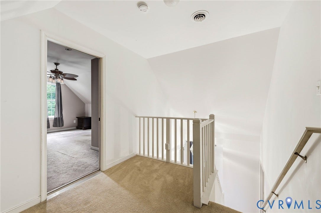 Carpeted hallway with a painted railing and handrail