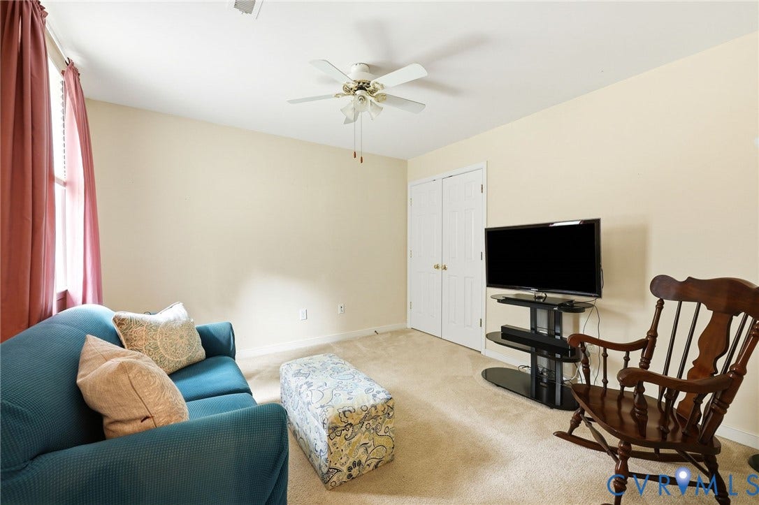 Neutral wall paint, ceiling fan, carpet flooring, and double-door closet
