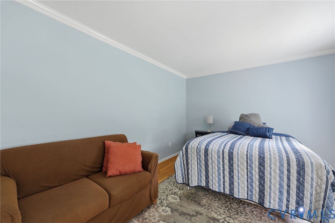 Recessed ceiling with crown molding, light blue wall paint, and wood-finish flooring
