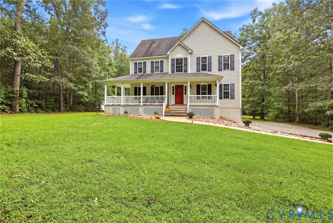 Two-story residence with a full-width covered porch, light-toned siding, and dark shutters