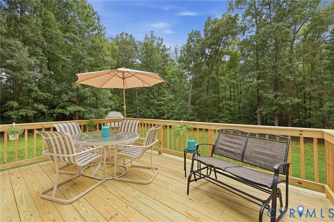 Expansive wood deck with natural wood railing overlooking a lush, treed backdrop