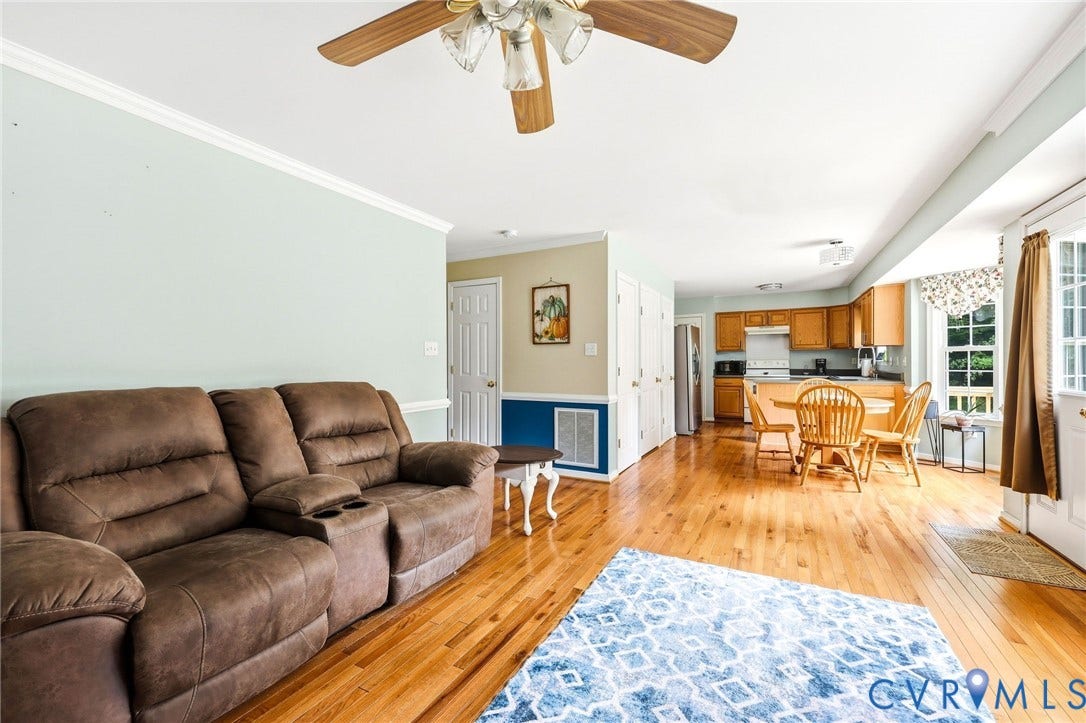 Hardwood flooring throughout, crown molding, ceiling fan, white paneled doors, and ample natural light from exterior door