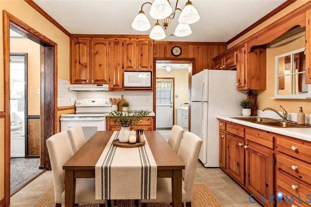 Wood-paneled kitchen featuring abundant wood cabinetry, white appliances, a double basin sink, and a tiled backsplash
