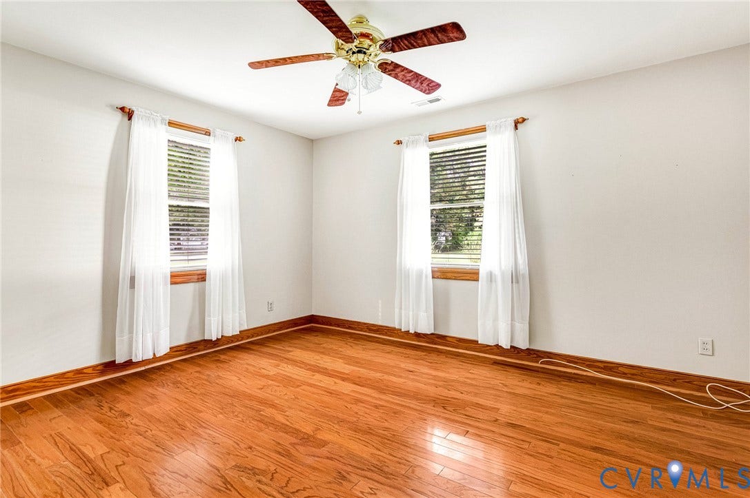 Hardwood flooring, two windows with blinds, and a ceiling fan with light fixture.