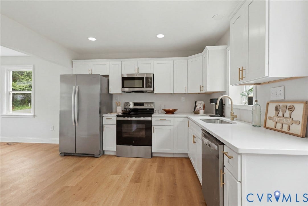 Kitchen featuring white cabinetry, light countertops, wood-finish flooring, and stainless steel appliances including a refrigerator, range, microwave, and dishwasher