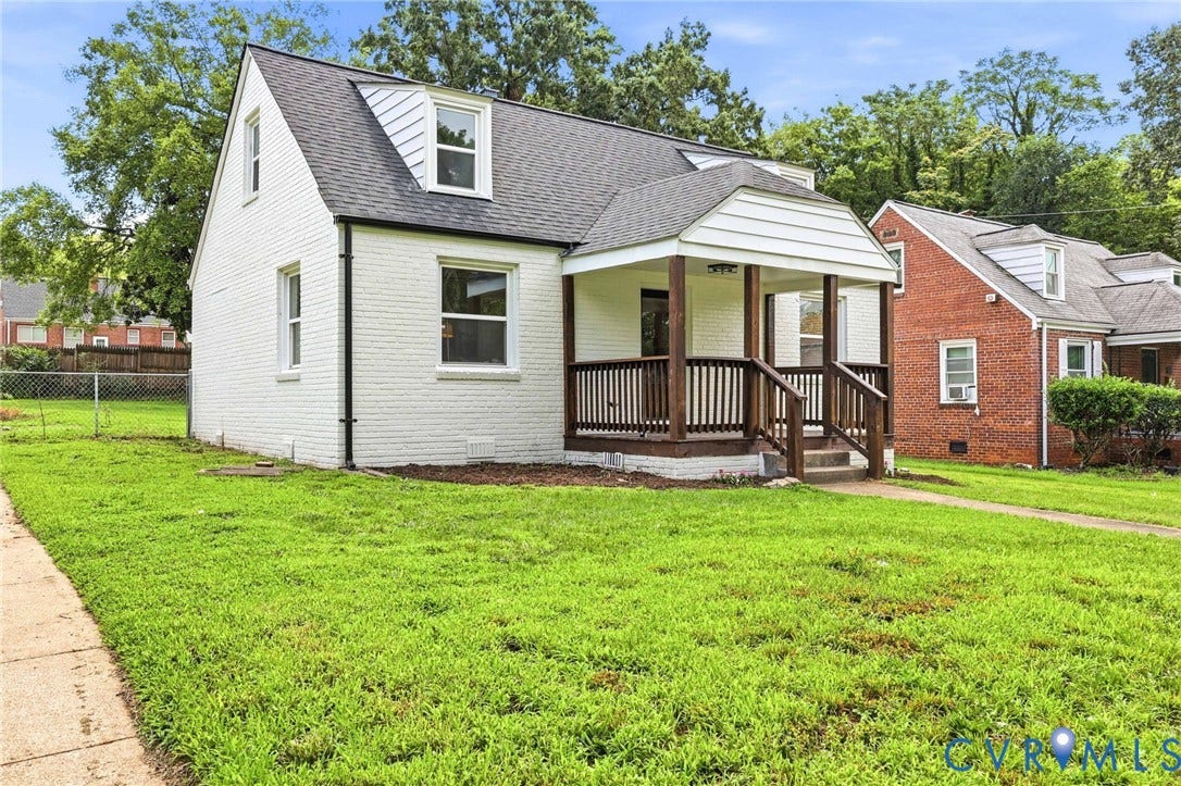 White brick exterior with a front porch featuring dark wood railings and posts