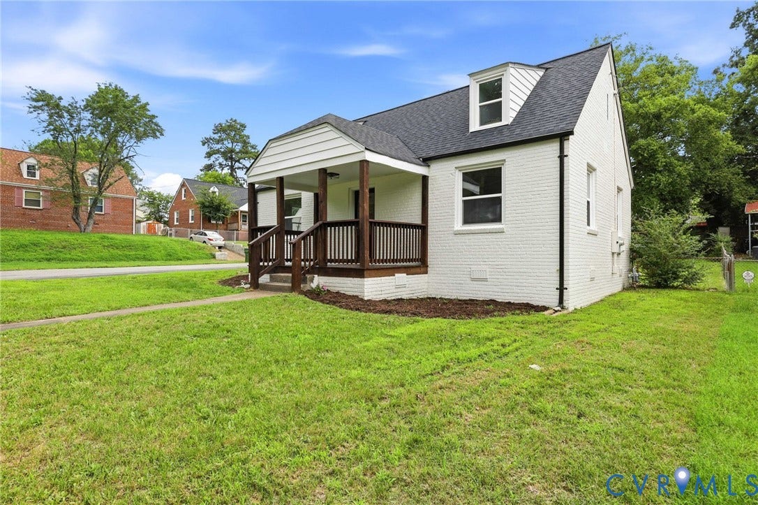 White painted brick exterior with a dark shingle roof