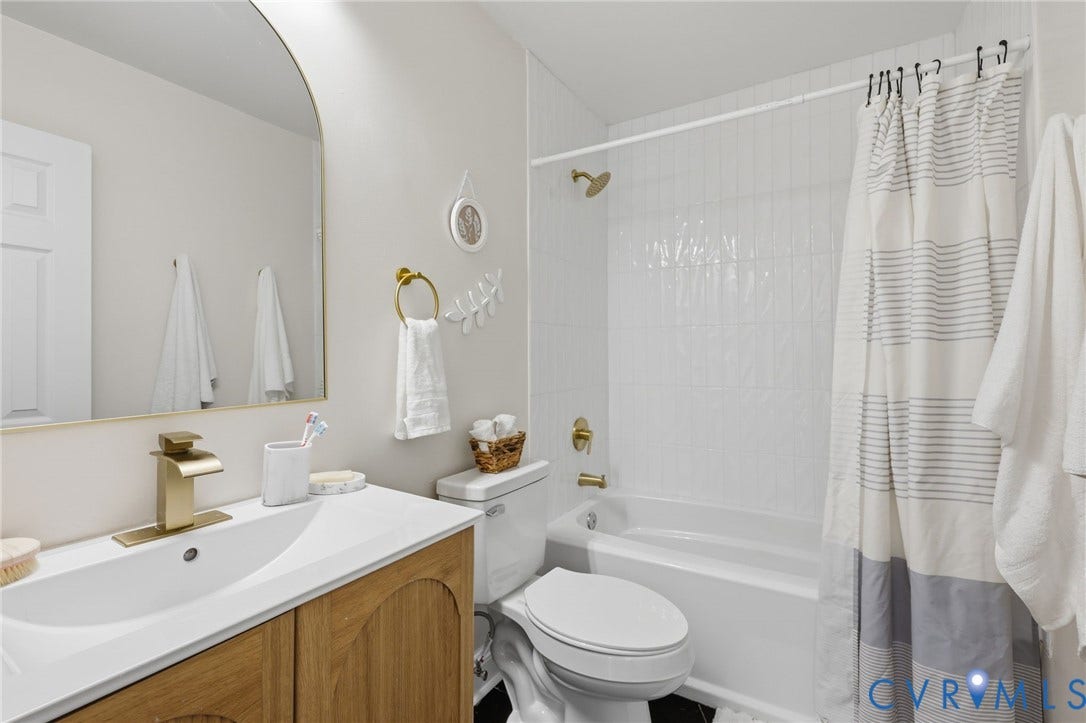 Bathroom featuring a single vanity with wood-finish cabinetry, a white countertop, and gold-tone fixtures