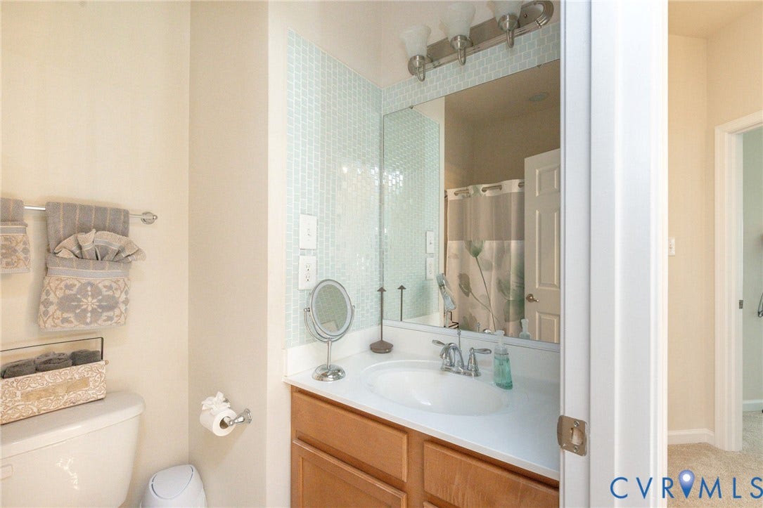 Vanity with a white countertop and wood-finish cabinetry, illuminated by a brushed nickel light fixture