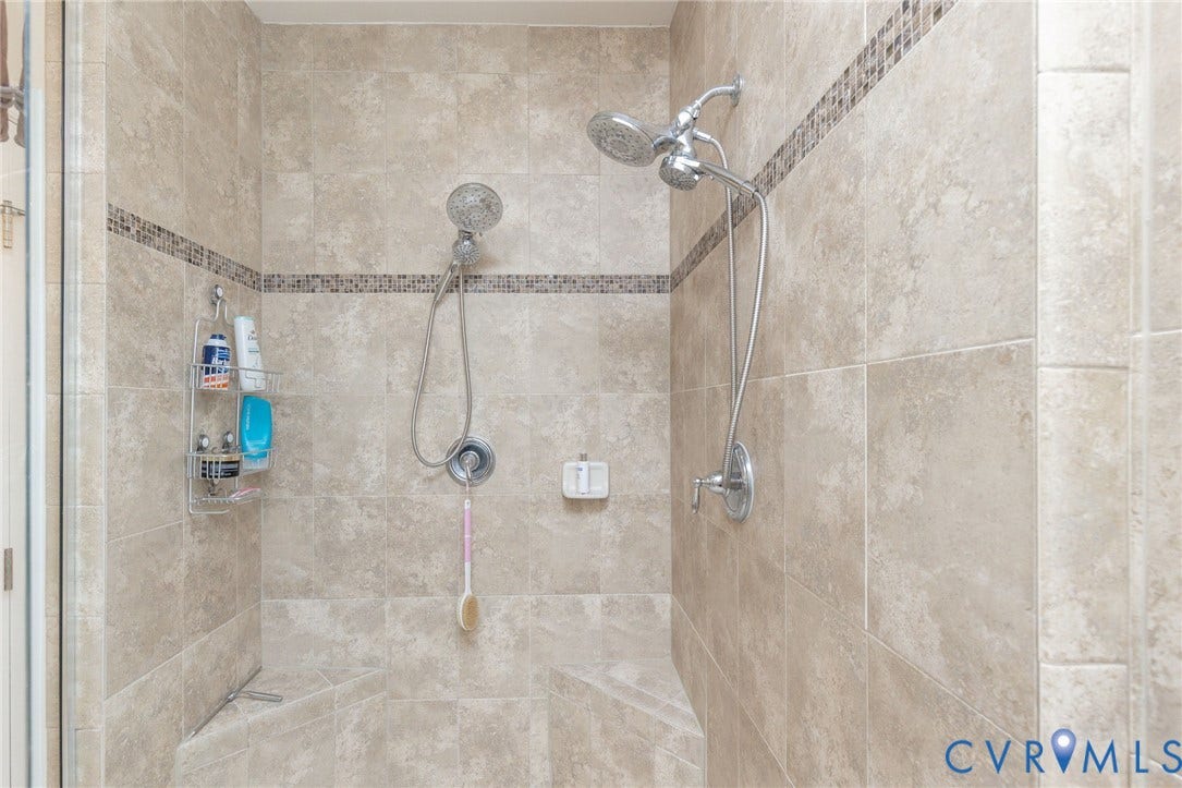 Tile shower with integrated mosaic accent band, dual shower heads, and built-in bench