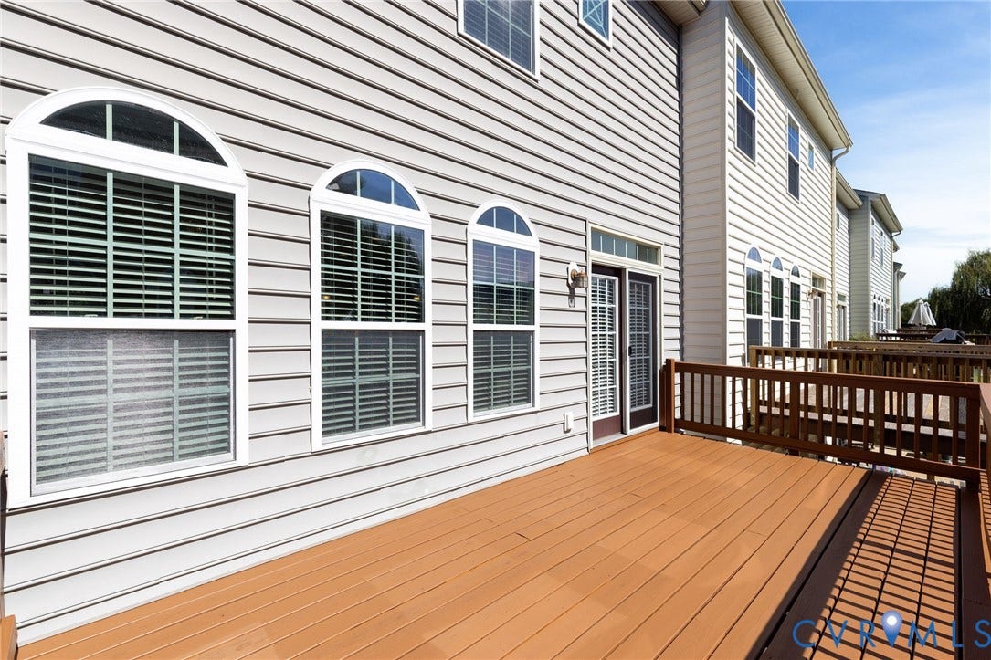 Expansive outdoor deck with wood-finish flooring, surrounded by a wood-finish railing