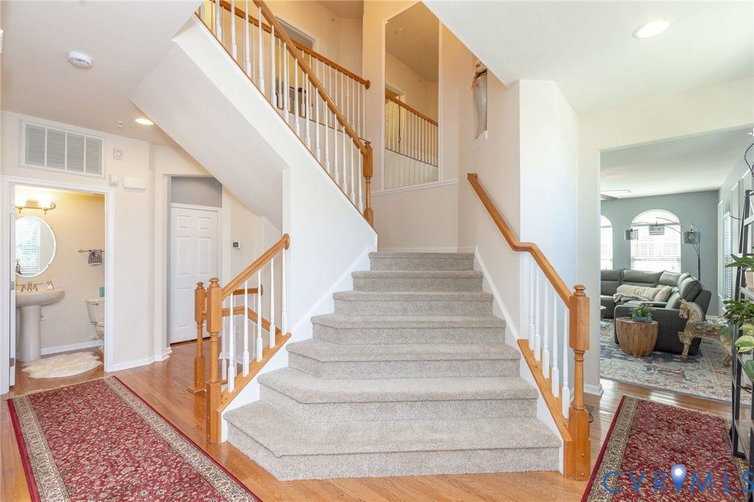Hardwood-finish flooring, carpeted staircase with wood banister and white spindles, recessed lighting, and a pedestal sink in the adjacent room