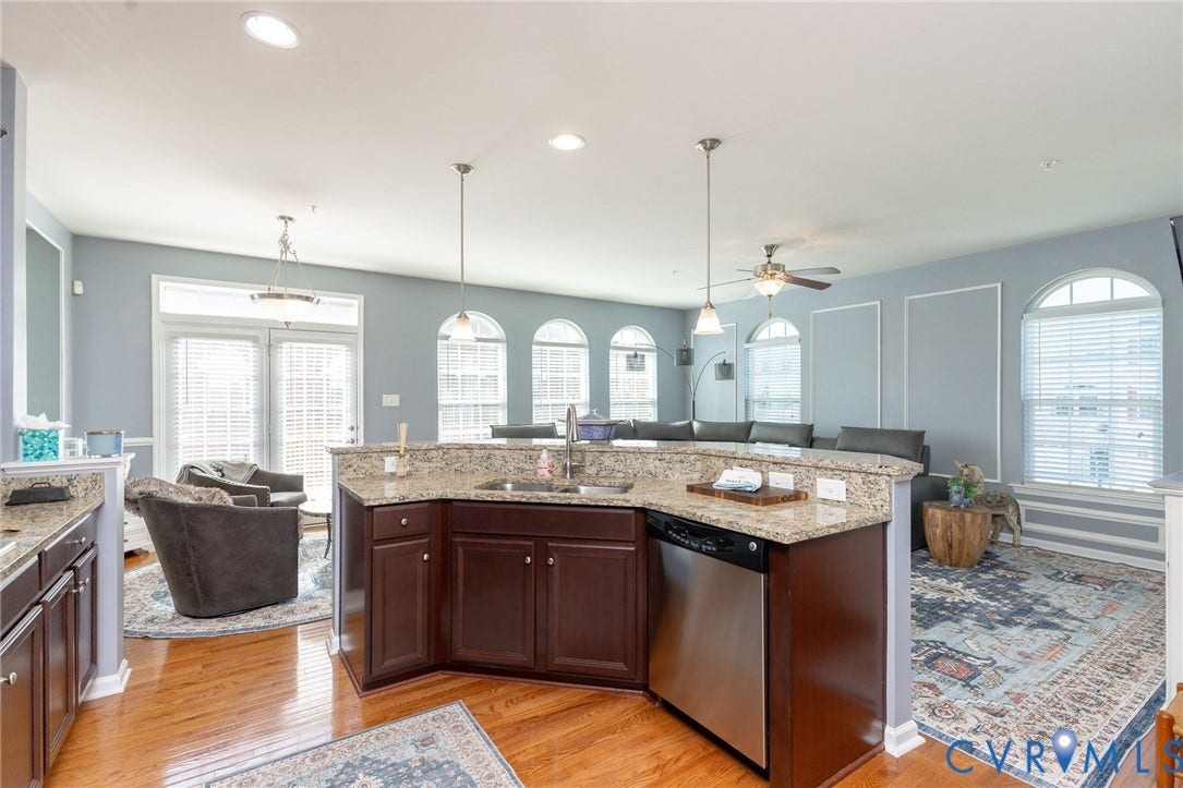 Kitchen island featuring a double-basin sink, stainless steel dishwasher, and granite countertops