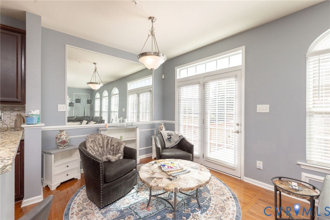Wood-finish flooring, half-wall with wainscoting, glass-paneled double doors with transom window, arched window, and granite-finish countertop