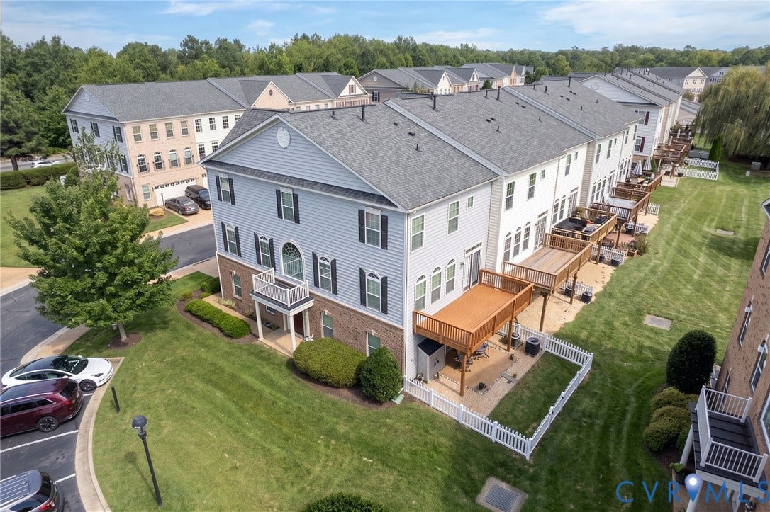 Three-story townhome with light blue siding and brick accents