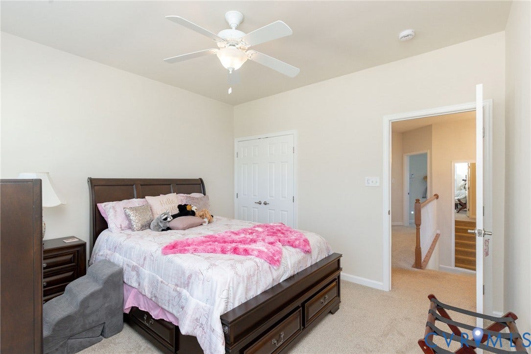 Neutral tone wall color, ceiling fan with integrated lighting, carpeted flooring, and a double-door closet