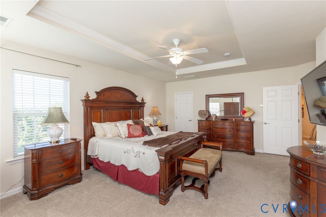 Tray ceiling with crown molding, ceiling fan, carpeted flooring, window with blinds, and white interior doors