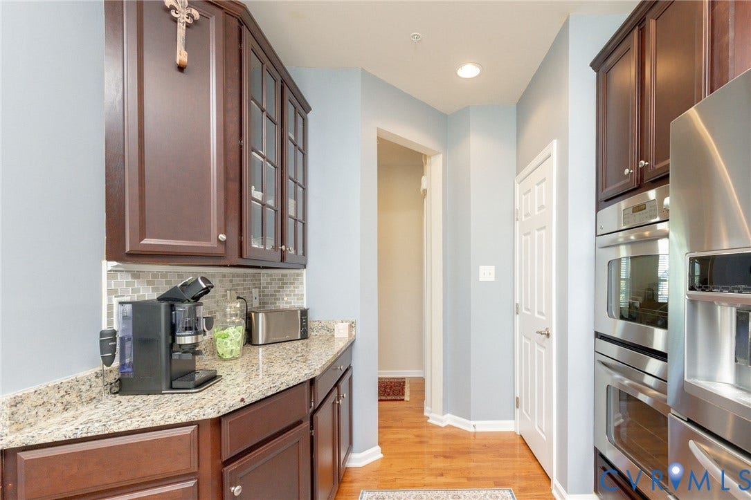 Granite-look countertops, tiled backsplash, built-in stainless steel double oven, and wood-finish flooring