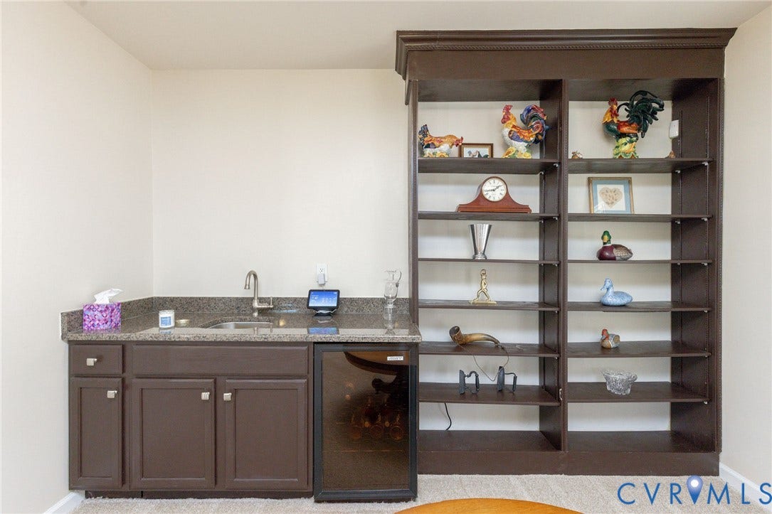 Built-in shelving, brown cabinetry, undermount sink, gooseneck faucet, and integrated beverage cooler