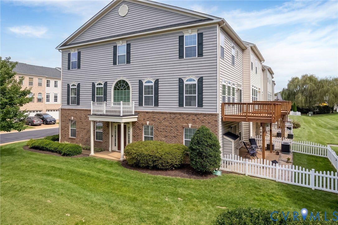 Multi-level exterior with brick and siding, featuring a covered entry porch, a second-story balcony, and a rear deck