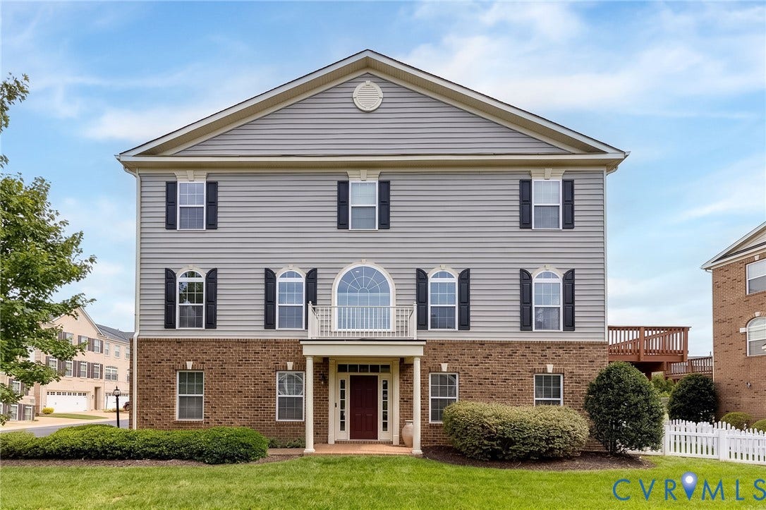 Three-story exterior featuring a brick facade, siding, and an arched window
