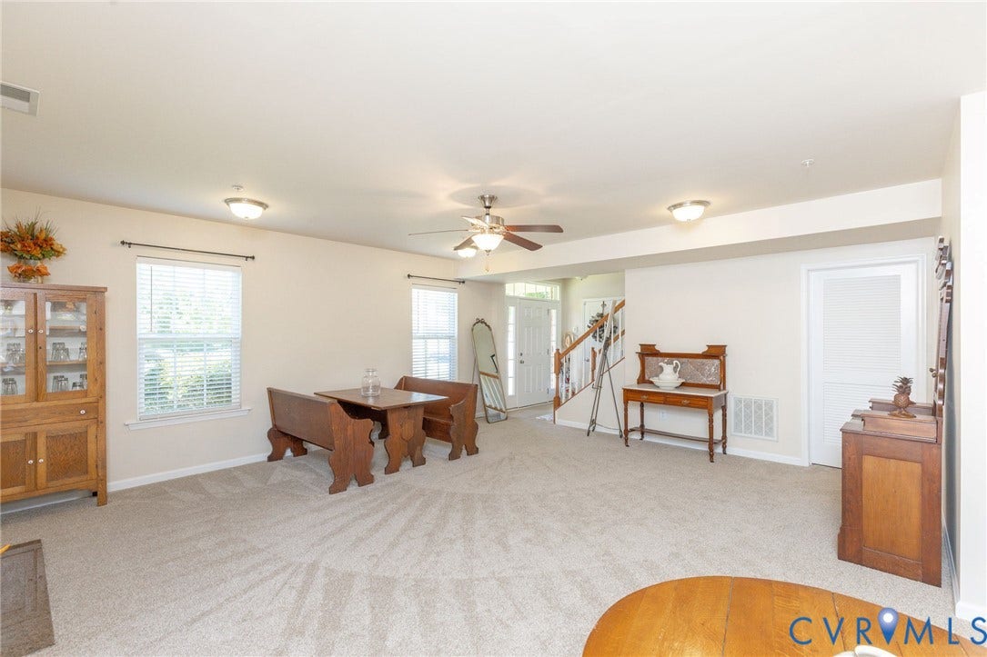 Carpeted living area with multiple windows, recessed lighting, ceiling fan, and a visible staircase