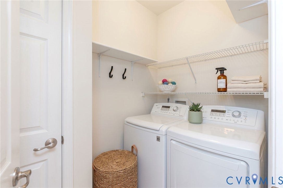 Integrated laundry appliances with white finishes, overhead wire shelving, and wall-mounted hooks