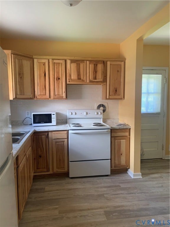 Kitchen featuring wood-finish cabinetry, light-toned countertops, and wood-finish flooring