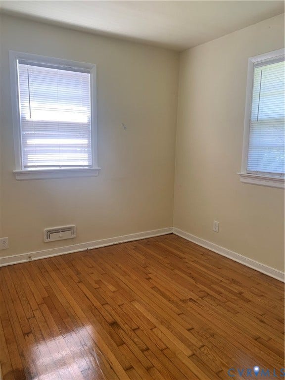 Wood-finish flooring with white trim and multiple windows