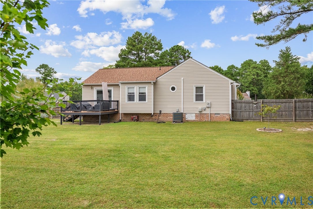 Expansive backyard featuring a manicured lawn, a large wooden deck, and a privacy fence