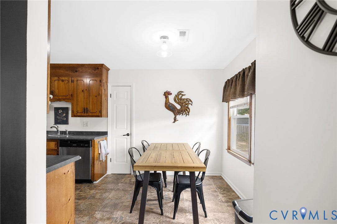 Kitchen featuring wood cabinetry, stainless steel dishwasher, and dark countertops
