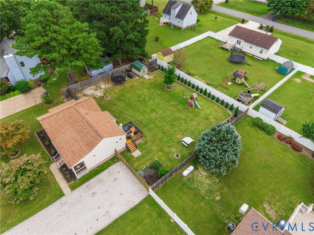 Expansive green lawn with mature trees and a gravel driveway