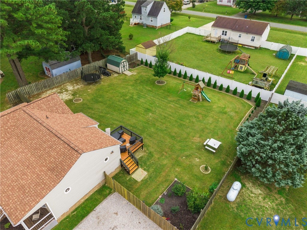 Expansive backyard featuring a wood deck, manicured lawn, and privacy fencing