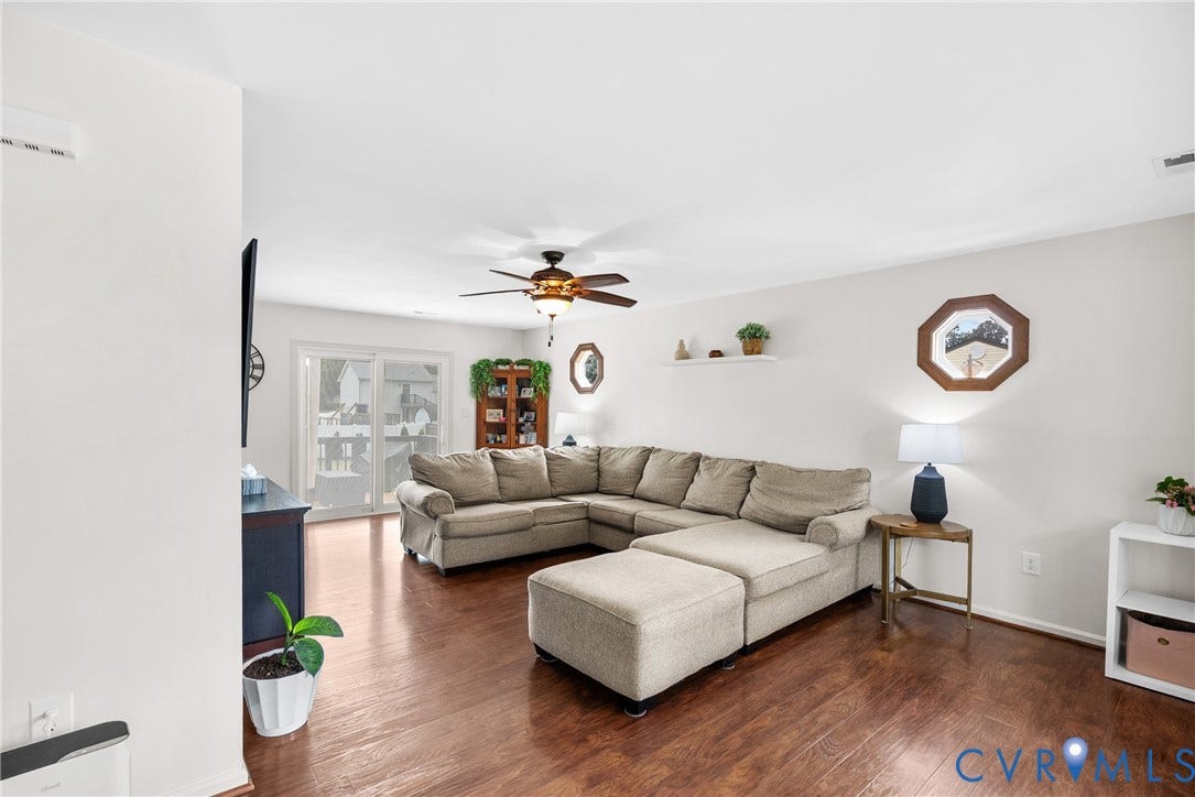 Hardwood-finish flooring, white walls, ceiling fan, sliding glass doors, and built-in shelving