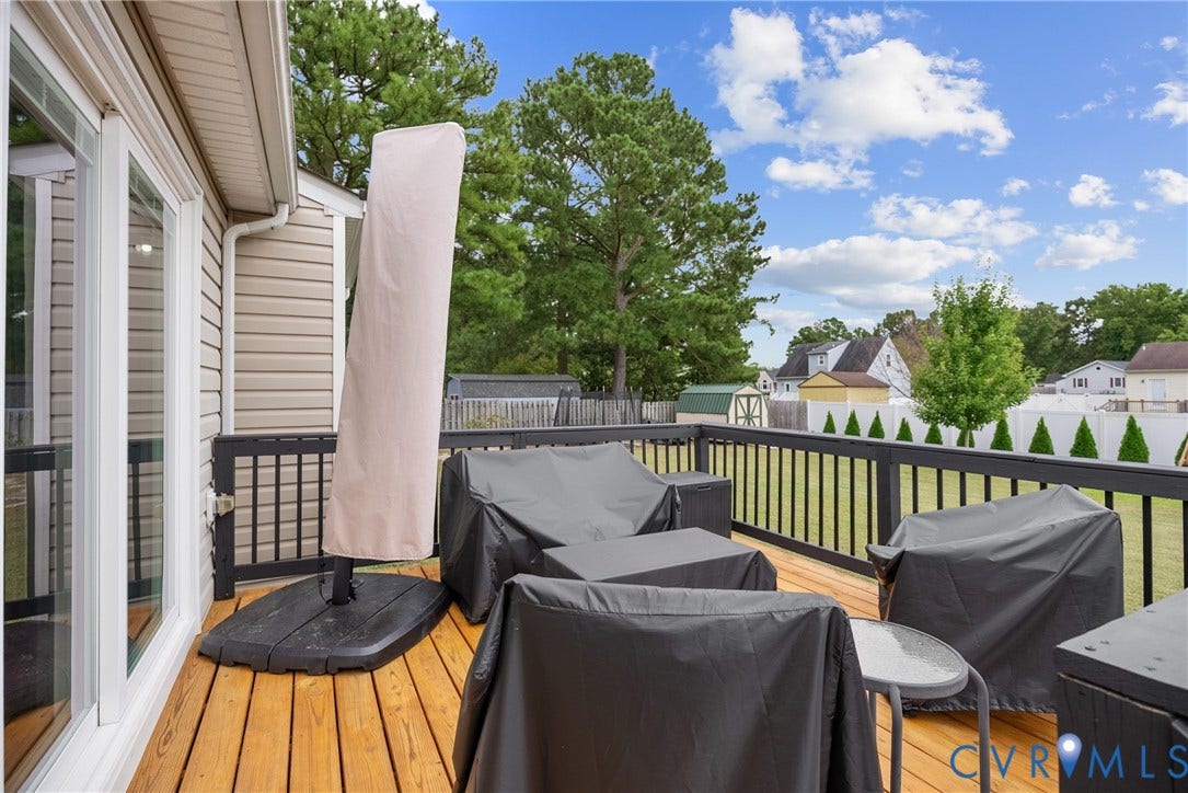 Expansive wood deck with dark railing and white vinyl siding