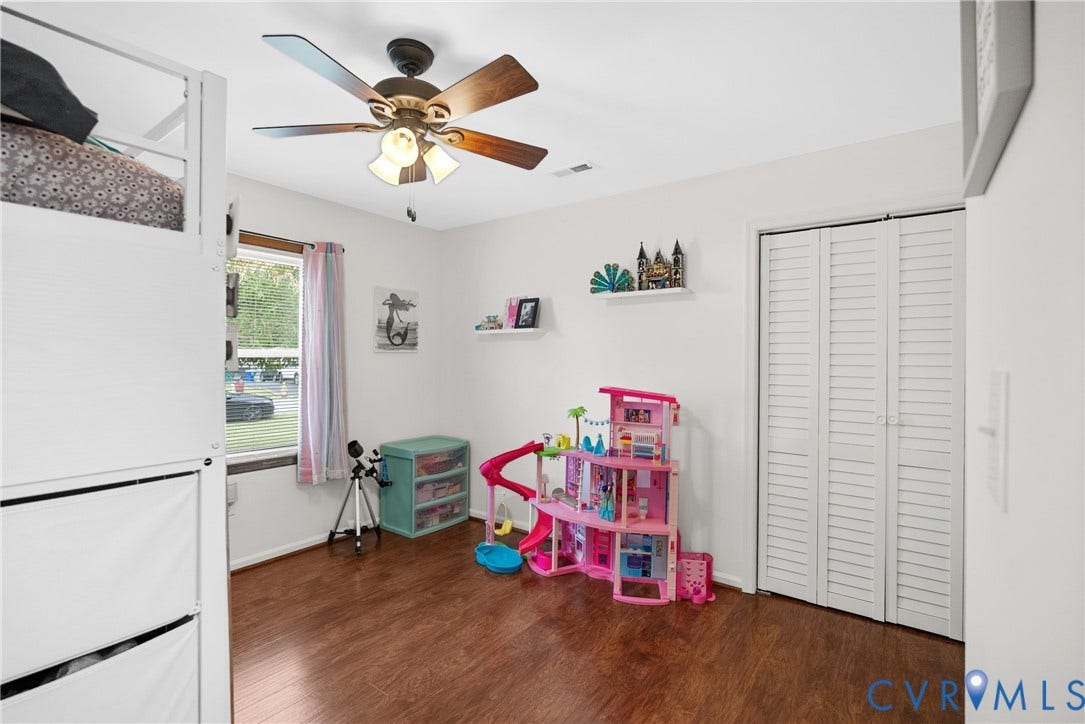 Wood-finish flooring, ceiling fan with integrated lighting, window with trim, white walls, and bi-fold louvered closet doors