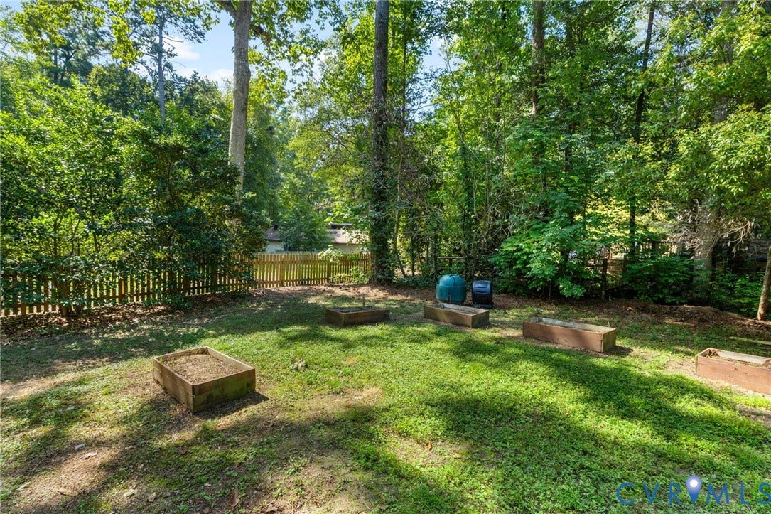 Expansive backyard featuring a manicured lawn, established trees, and a wooden picket fence