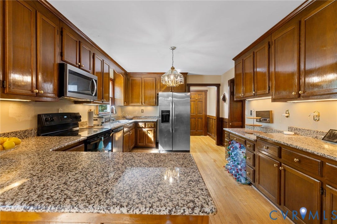 Granite countertops, stainless steel appliances, wood-finish flooring, recessed lighting, and a decorative chandelier
