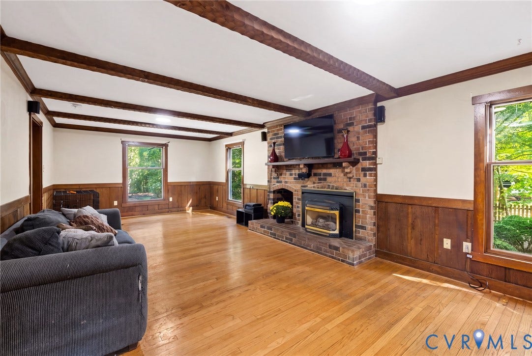 the family room is accented with chair rail, wainscotting, crown moulding and ceiling beams.