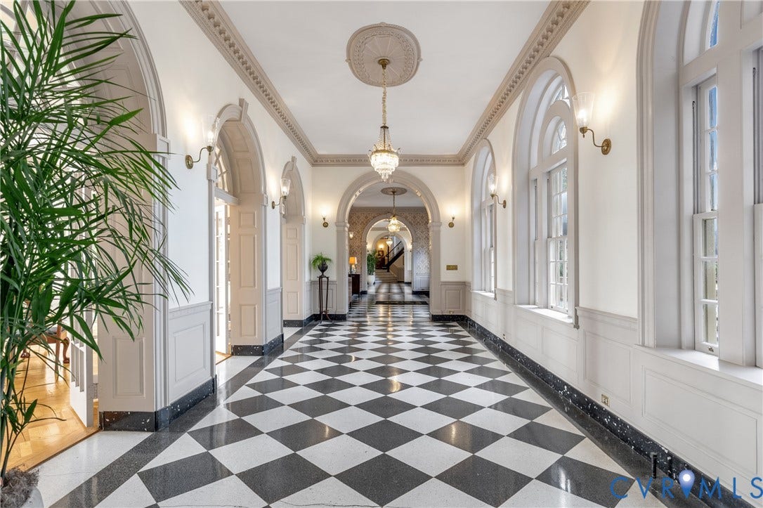 5621 Cary Street Road, #U4, Wilton, Richmond, VA 23226 Grand gallery hall featuring arched entryways, black-and-white checkered stone flooring, decorative crown molding with ceiling medallions, dual-tone wainscoting, and crystal chandeliers