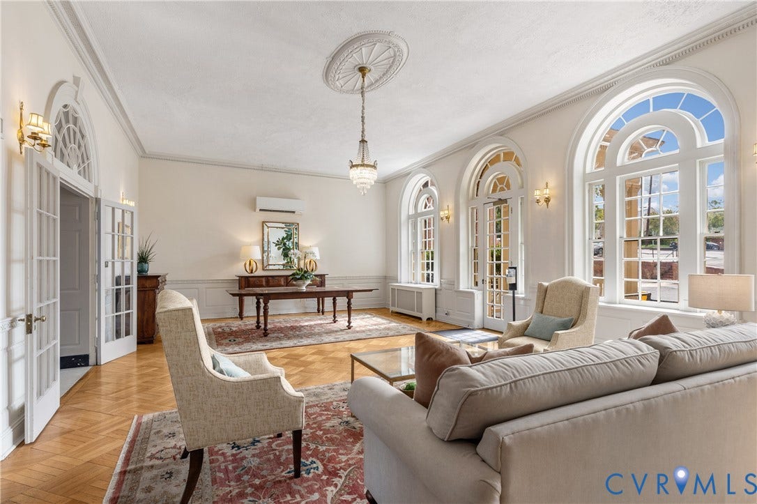 5621 Cary Street Road, #U4, Wilton, Richmond, VA 23226 Living space featuring herringbone-patterned wood flooring, arched windows with fanlight detailing, crown molding, wall paneling, and an ornate ceiling medallion with a crystal chandelier