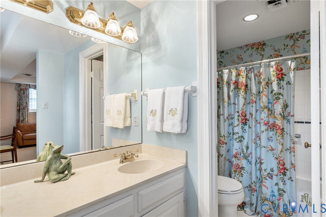 5621 Cary Street Road, #U4, Wilton, Richmond, VA 23226 Full-width wall mirror, vanity with integrated basin, brass-finish lighting fixture, and white cabinetry
