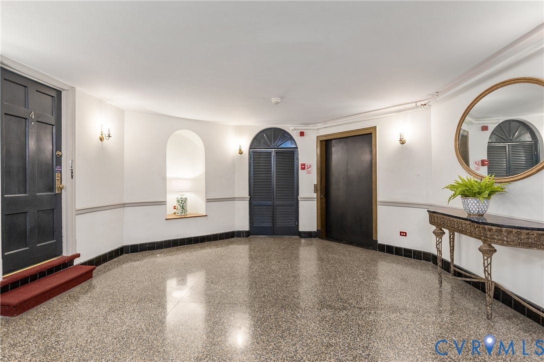 5621 Cary Street Road, #U4, Wilton, Richmond, VA 23226 Polished terrazzo flooring, recessed wall niche, arched doorway with glass transom, high-gloss paneled doors, and crown molding detail