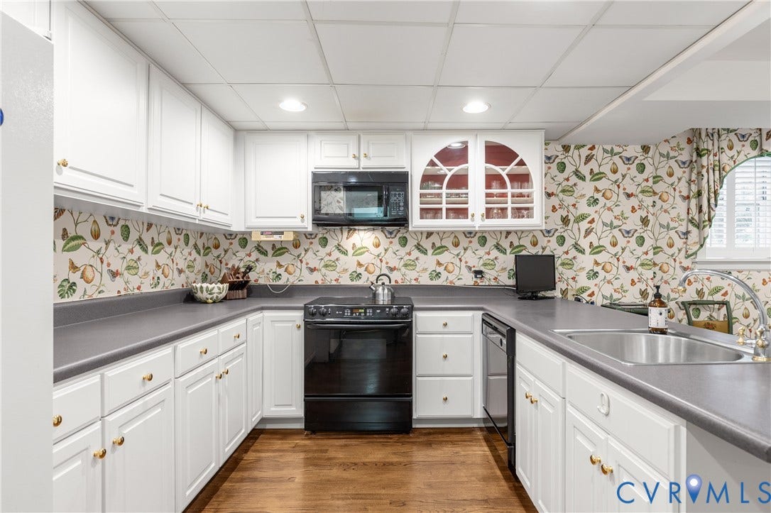 5621 Cary Street Road, #U4, Wilton, Richmond, VA 23226 Kitchen featuring white shaker-style cabinetry, solid-surface countertops, built-in glass-front upper cabinets, stainless steel sink, and wood-finish flooring