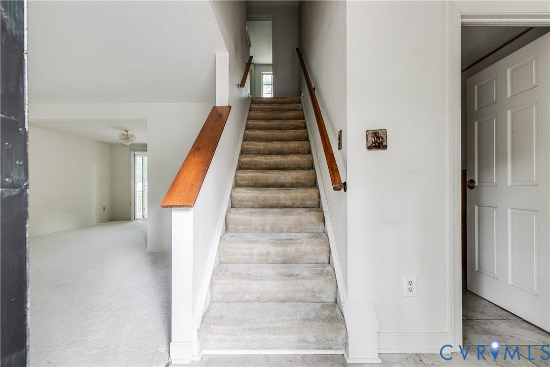 Staircase with wood handrail and carpeted treads