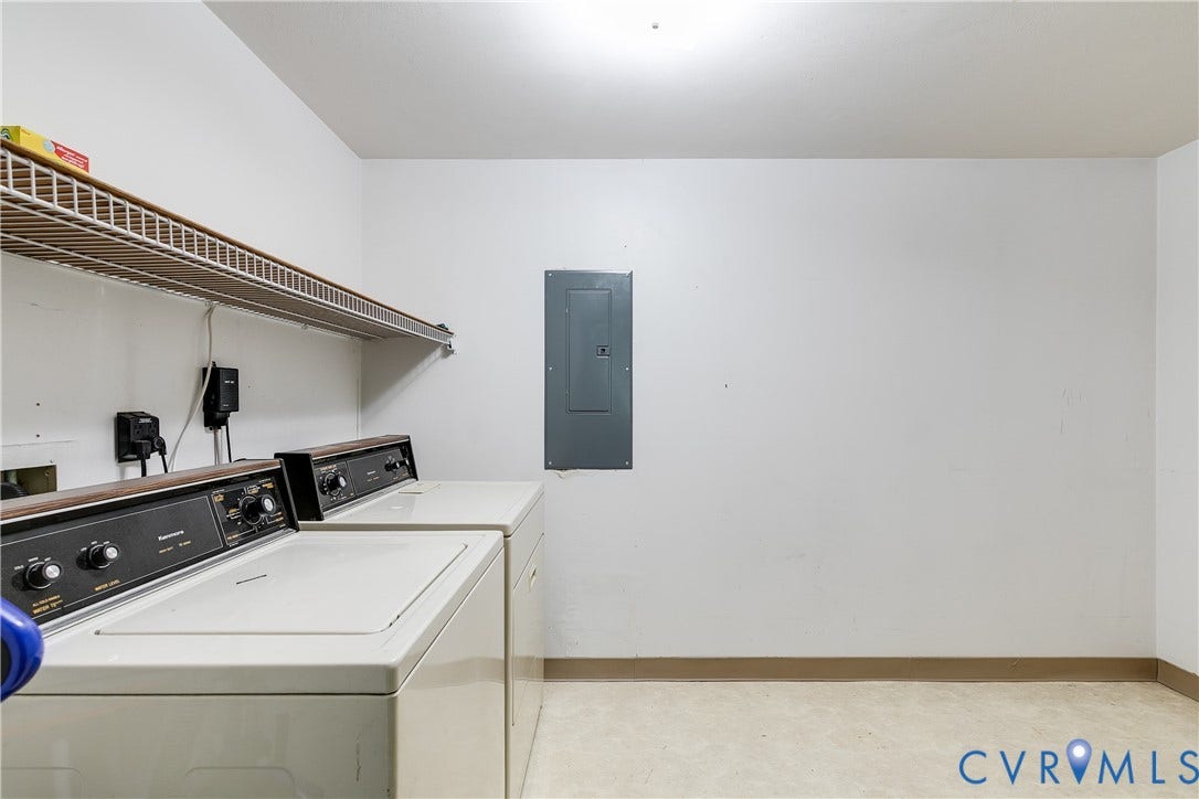 Laundry area with a wire shelf, wall-mounted electrical panel, and vinyl plank flooring