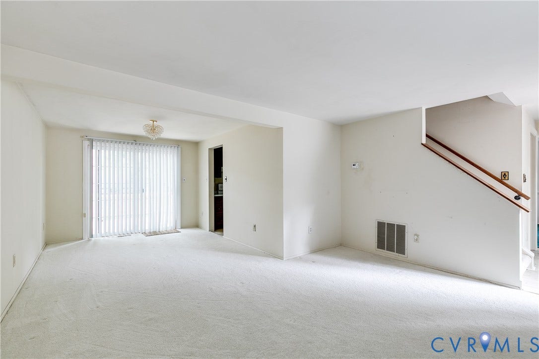 Wall-to-wall carpeting with a sliding glass door and vertical blinds